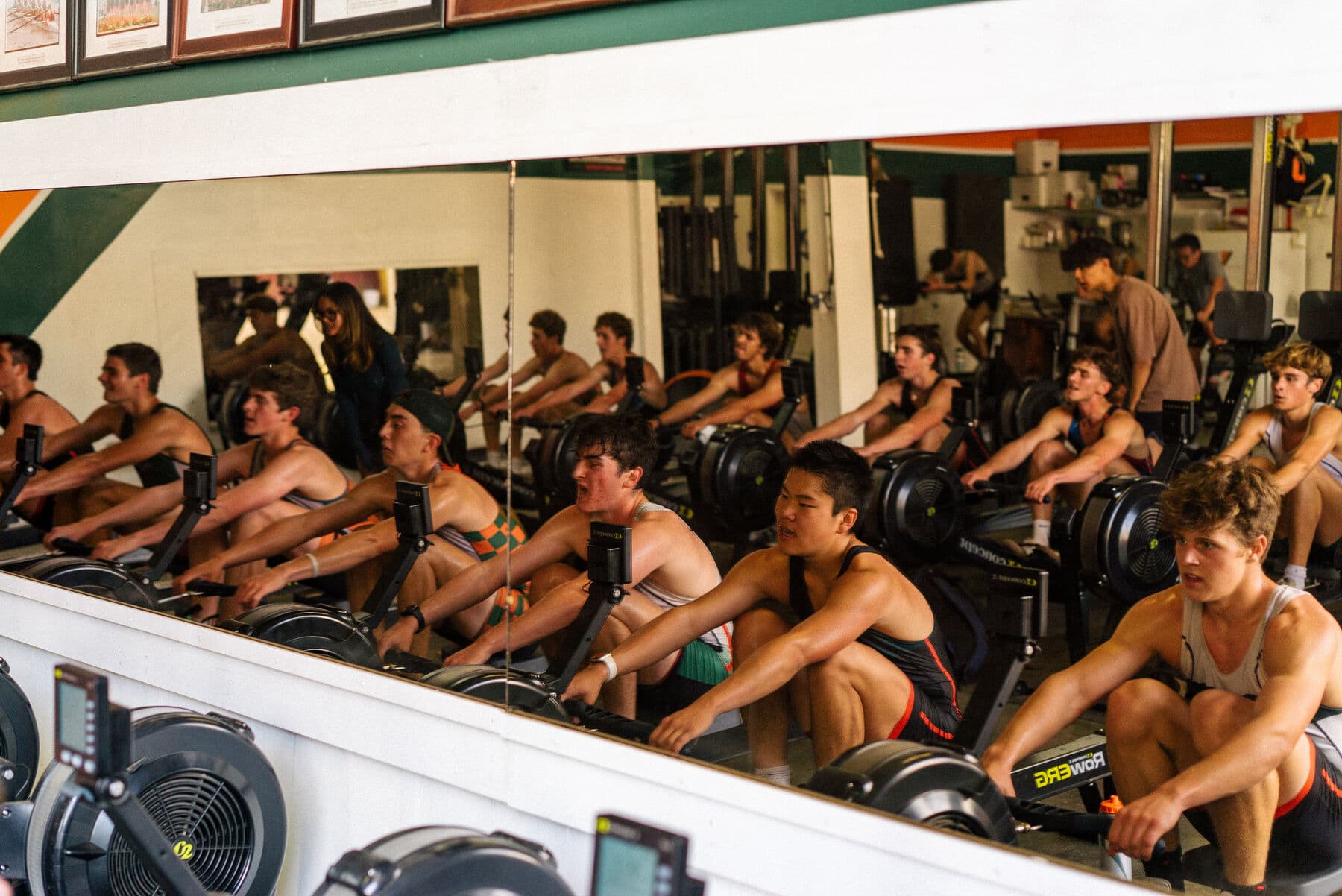 Rowers side by side on ergs in the boathouse during a hard piece