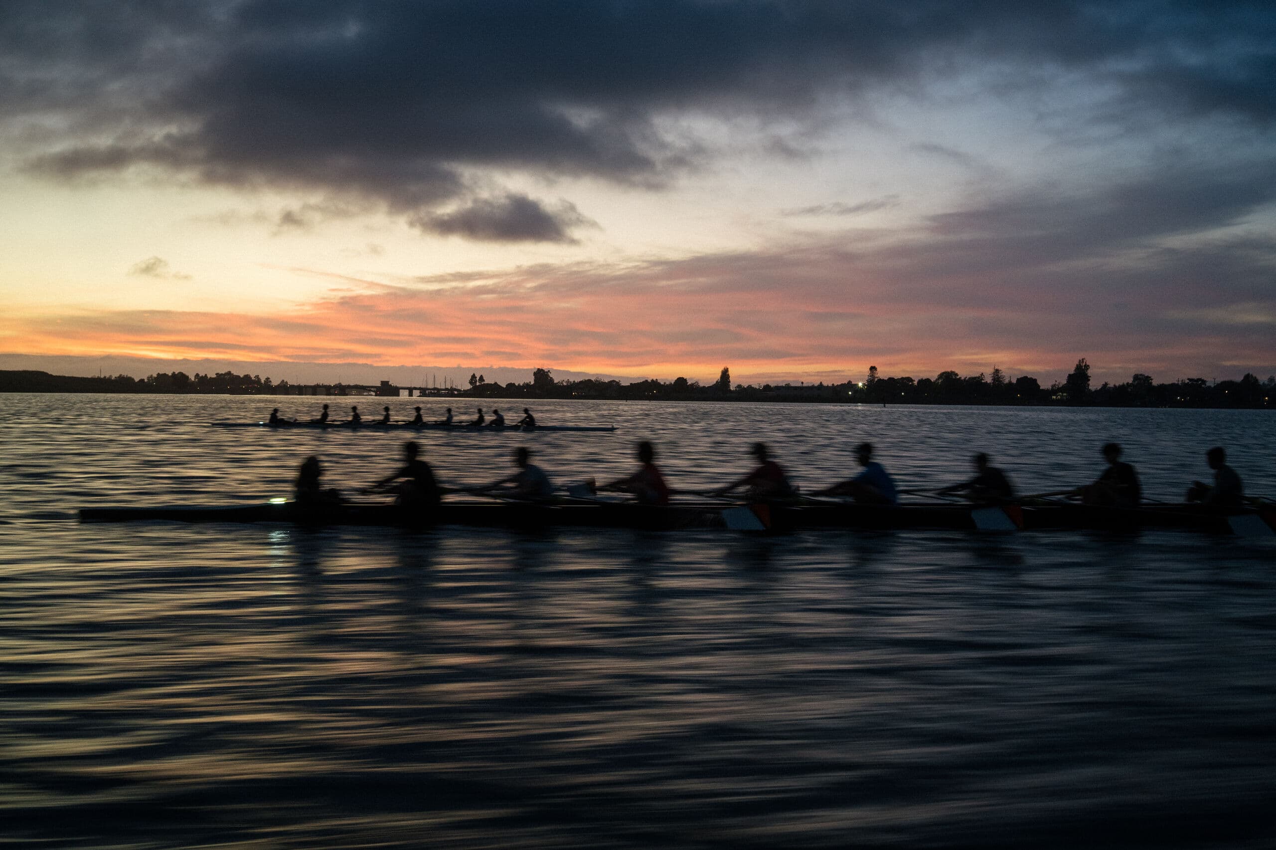 An eight silhouetted against a violet and gold sunset on flat water