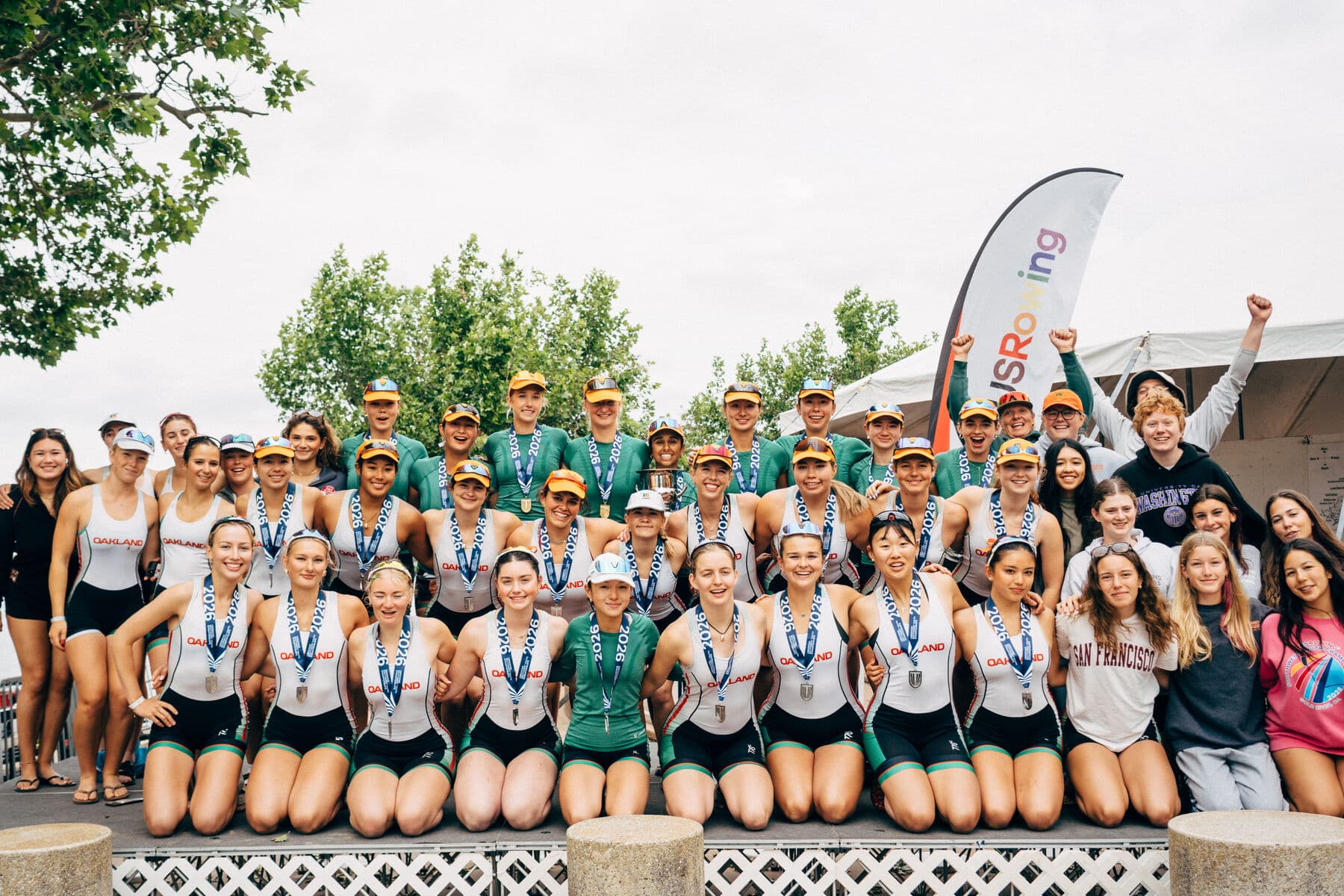 The women's team fills the awards stage at regionals, medals on and the trophy held high