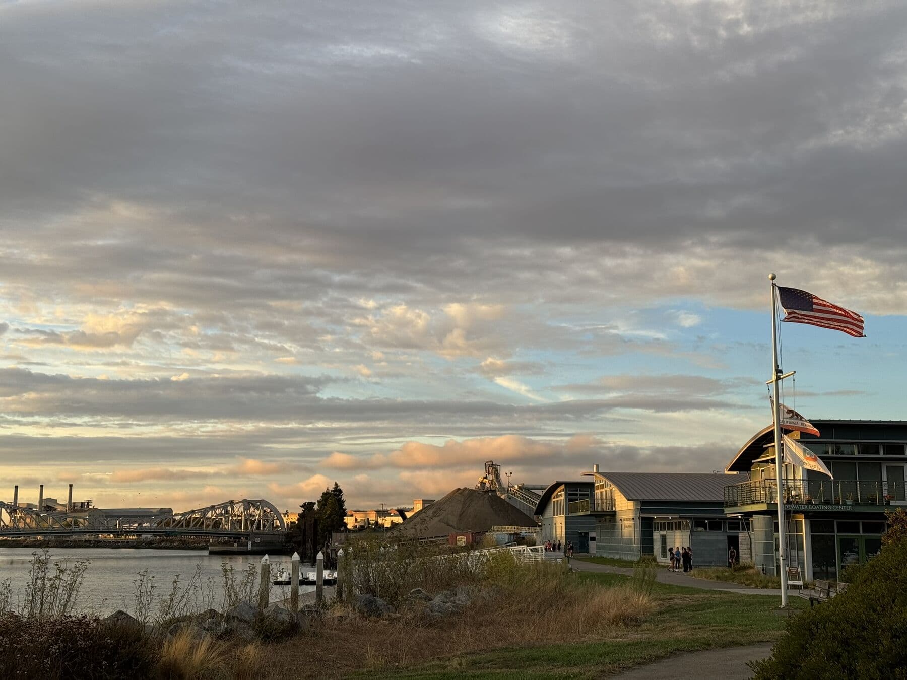 The Tidewater Boating Center at sunset, flag flying, the High Street bridge and the Estuary beyond