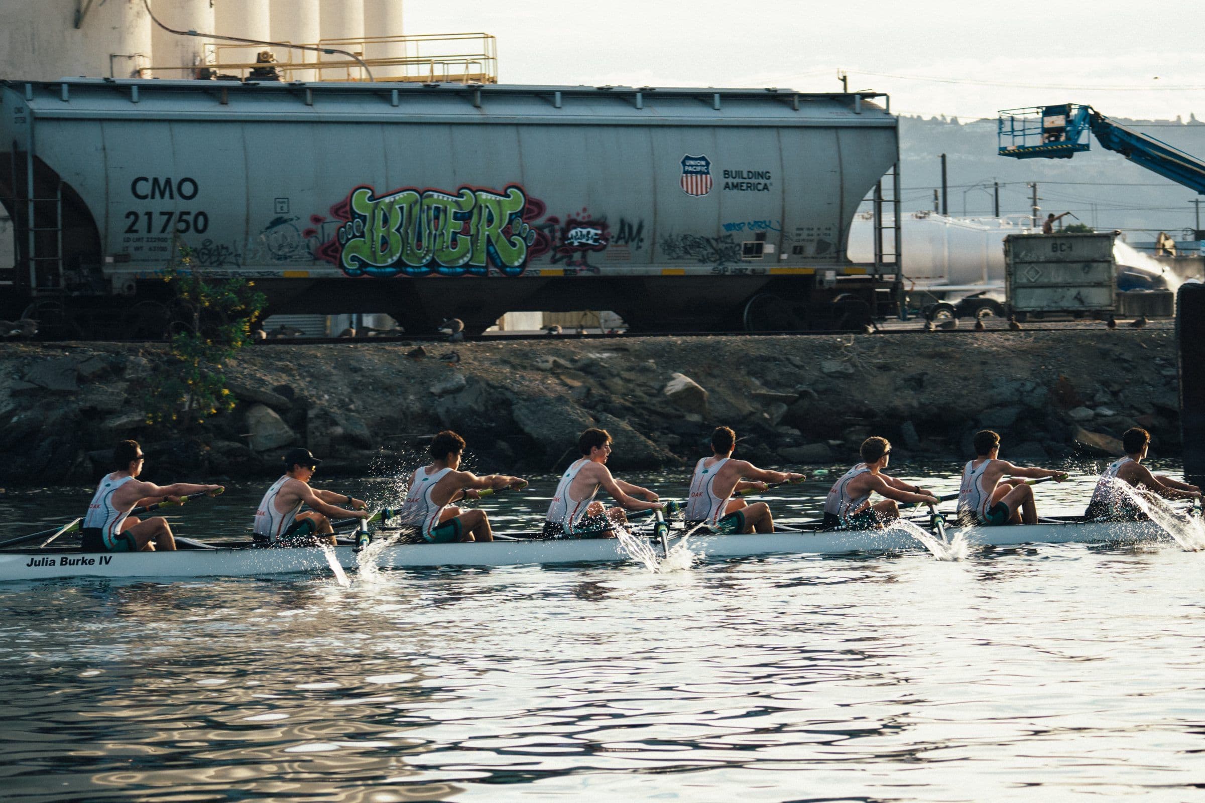 The men's eight races past a freight train on the Estuary shore at Head of the Estuary