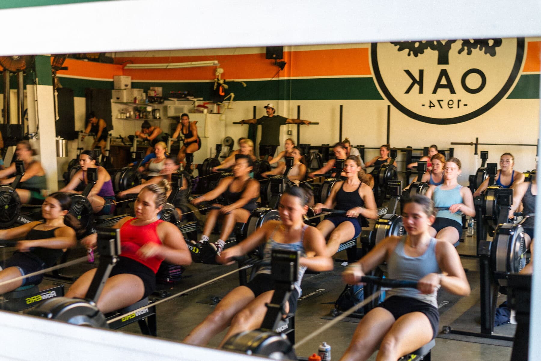 The women’s squad training side by side on ergs under the OAK 1974 mark