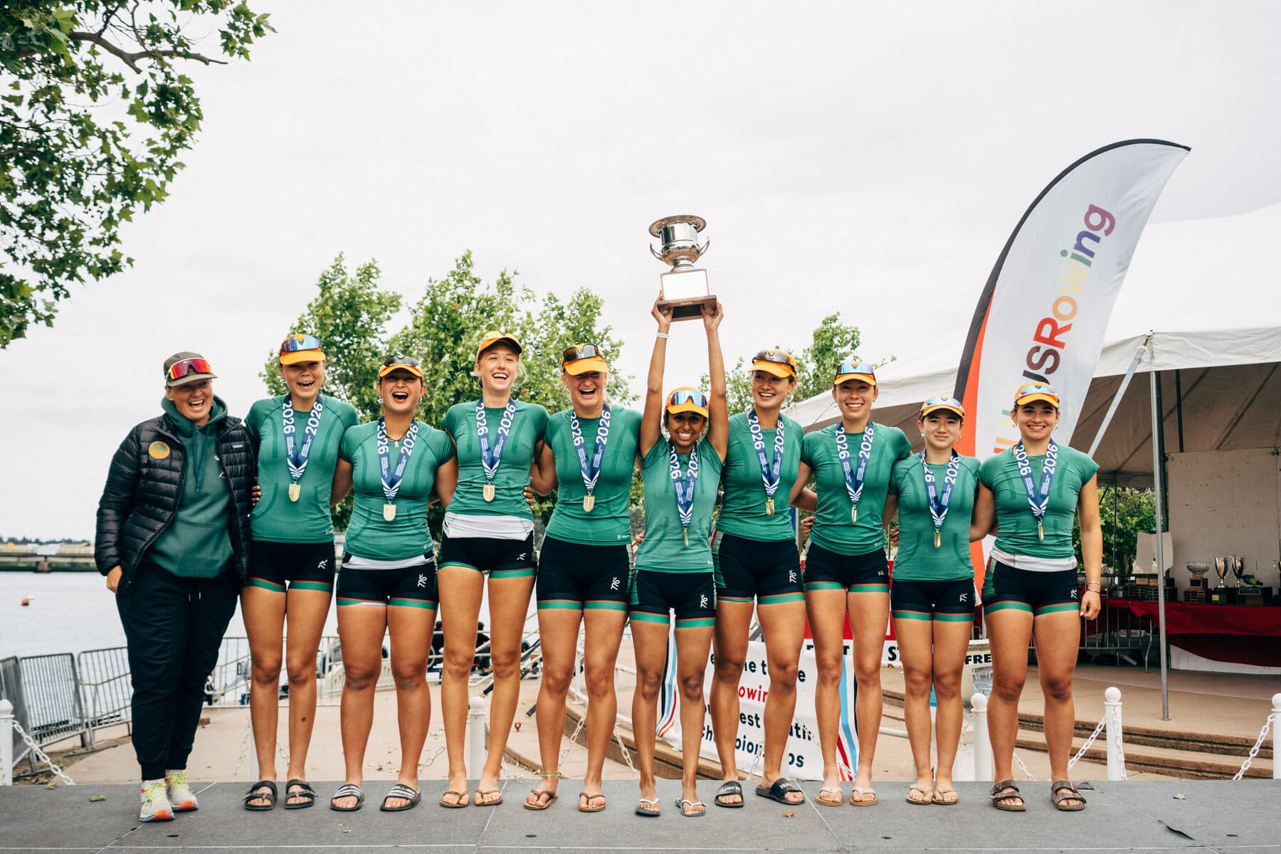 The women's eight lifts the team trophy together, gold medals around their necks