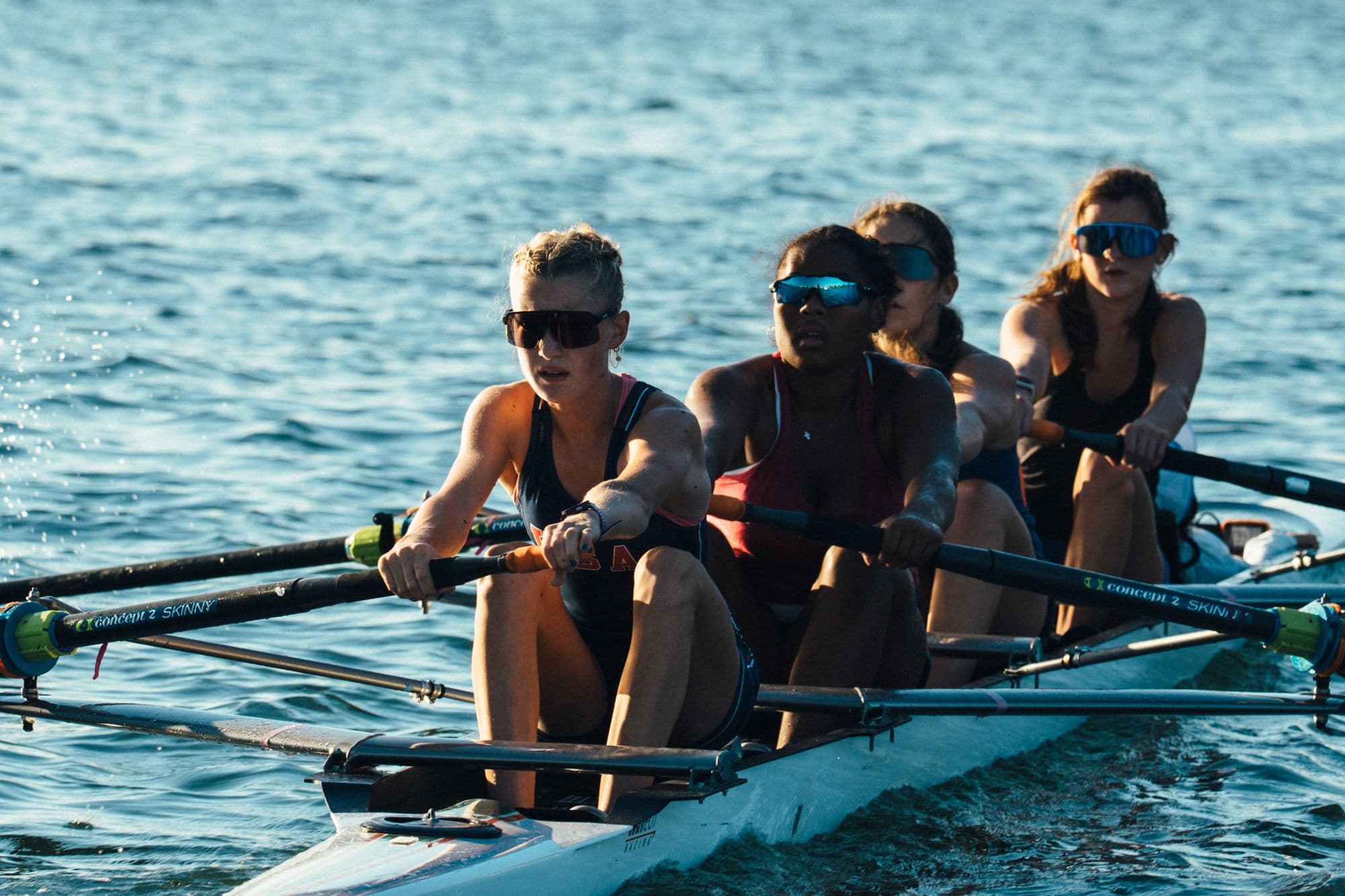 A women's four rows toward the camera in late afternoon light on the Estuary